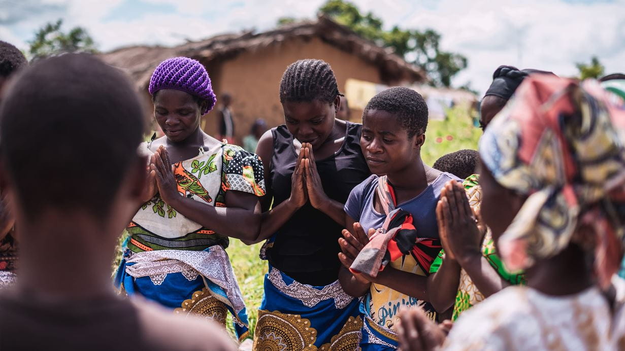 A group of people standing praying in a circle