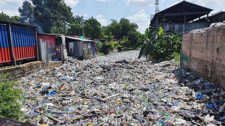 A flooded road filled with plastic waste.