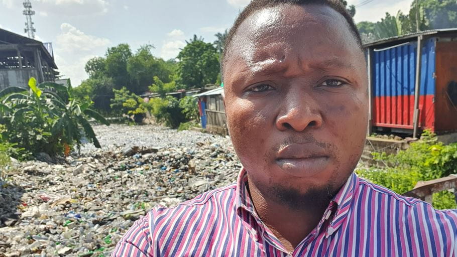 Alphonse Mata, from our Democratic Republic of Congo Team, next to riverbeds of plastic waste.