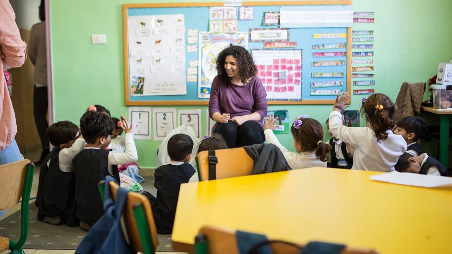 A teacher sitting with a group of children