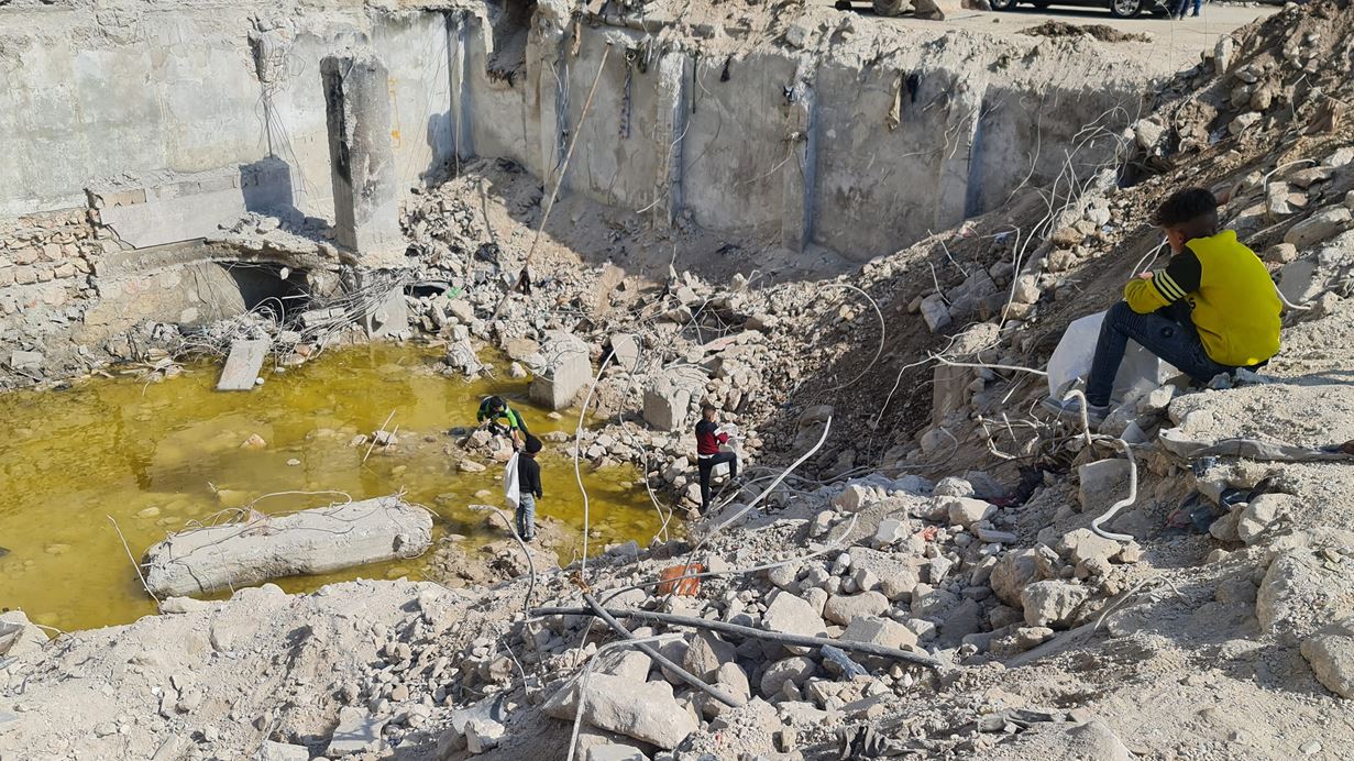 Children playing amongst the rubble of buildings