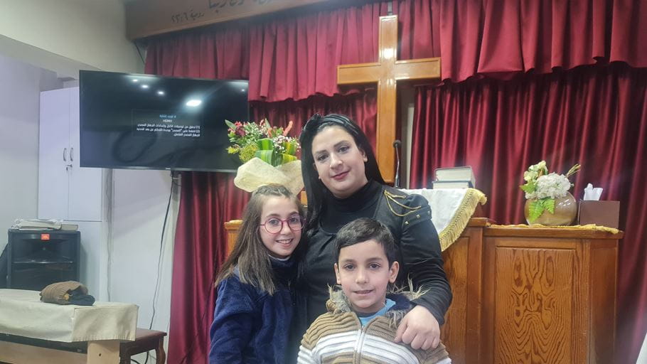 A woman and her two children standing in a church room