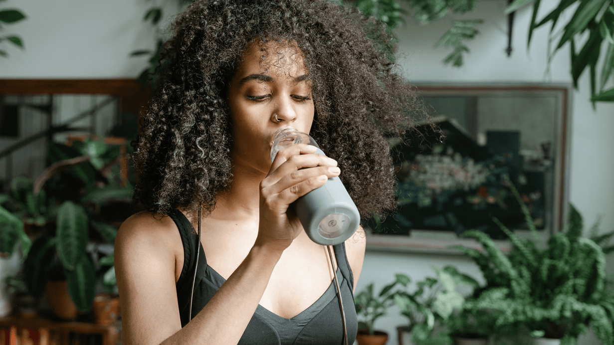 A woman drinking from a resuable water bottle.