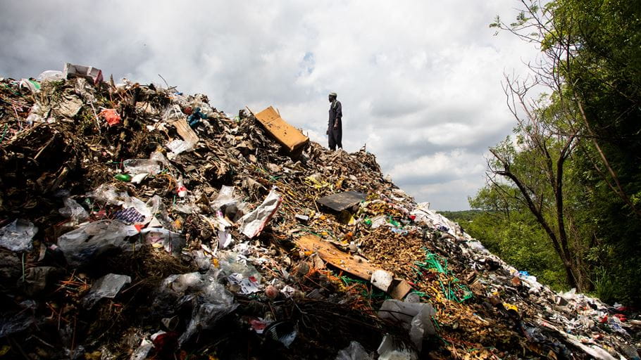 Kelvin Swai, a waste picker, standing by a pile of trash.
