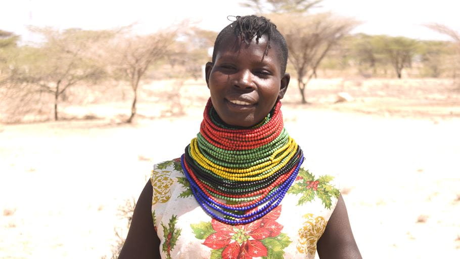 A smiling woman wearing a large amount of colourful necklaces