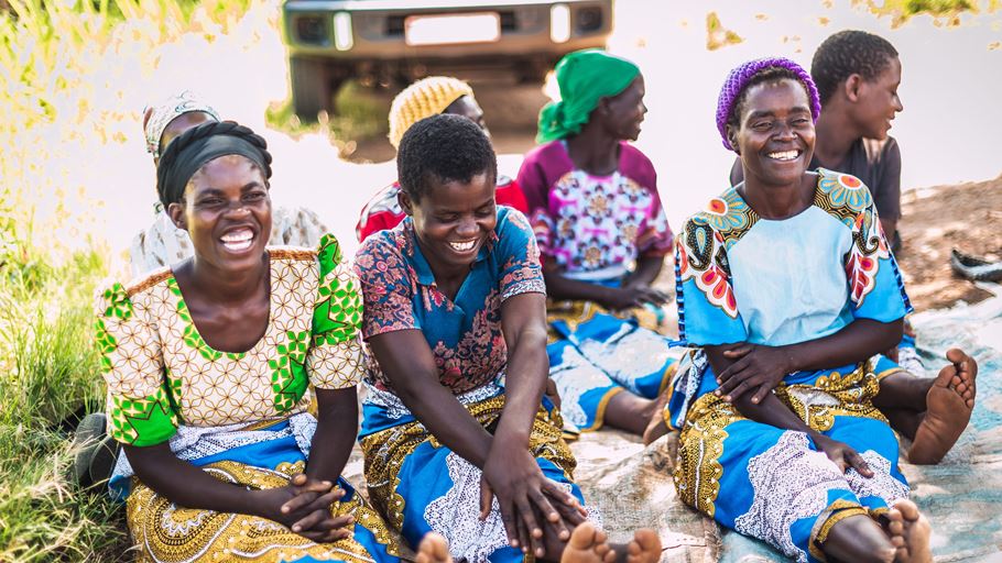 A group of women in colourful clothing sitting together on the floorA group of women in colourful clothing sitting together on the floor