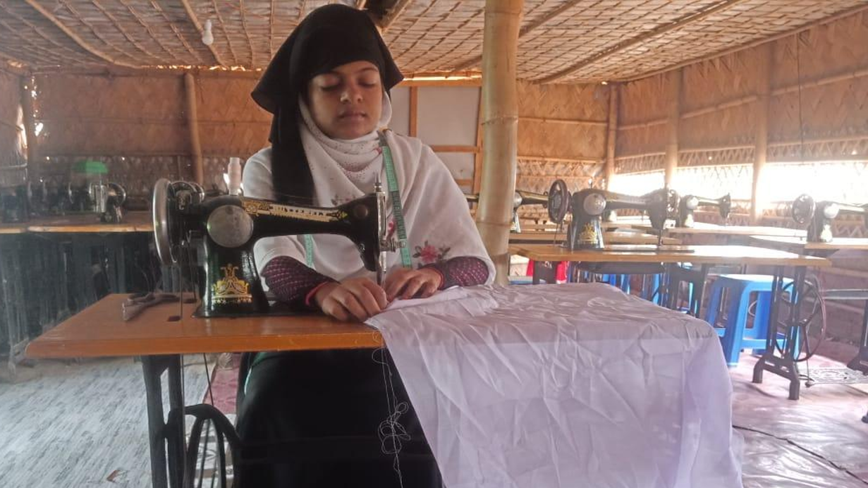 Aalia, a refugee from Myanmar, sits sewing at her sewing machine in Cox's Bazar refugee camp. She received sewing training from Tearfund's local partner.