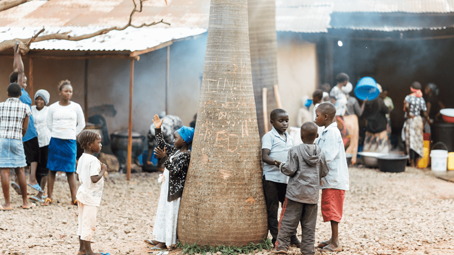 Young children play around the trunk of a large tree in a camp for internally displaced people in Nigeria. Conflict and climate disasters have left millions of children under the age of five acutely malnourished.