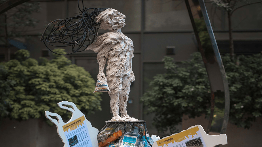 A sculpture of a young person on top of a pile of rubbish