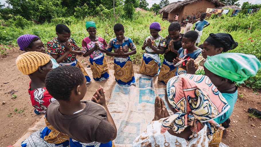 Women kneel and pray in a circle.