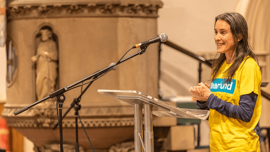 Tearfund's Ruth Valerio speaking into a microphone in a church gathering.