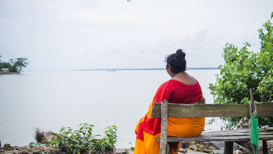 Komola sits on a bench looking out over the dam