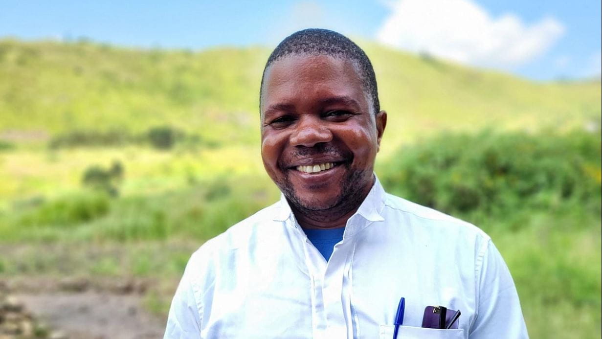 Desire, a man wearing a white shirt, smiles at the camera