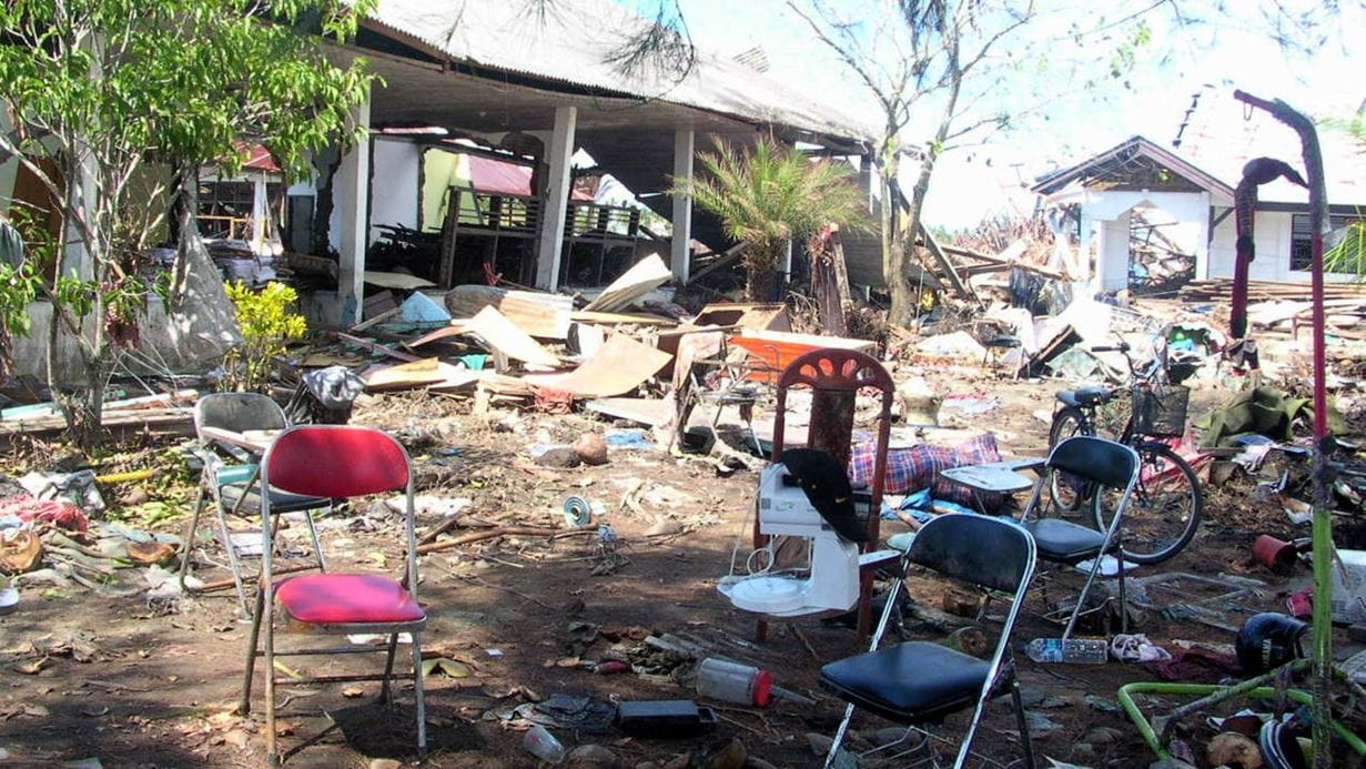 A few chairs stand outside the shell of a destroyed building - possibly a school.