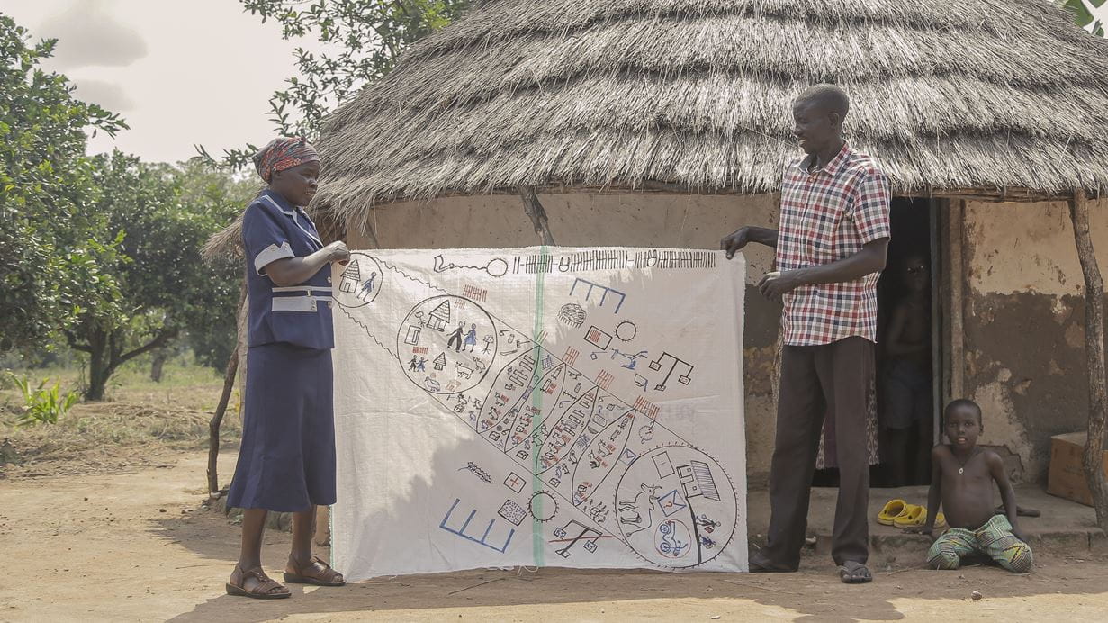 John and Helen hold the vision map between them that John drew on a piece of canvas. It shows his plans for working his way out of poverty and transforming his circumstances. 