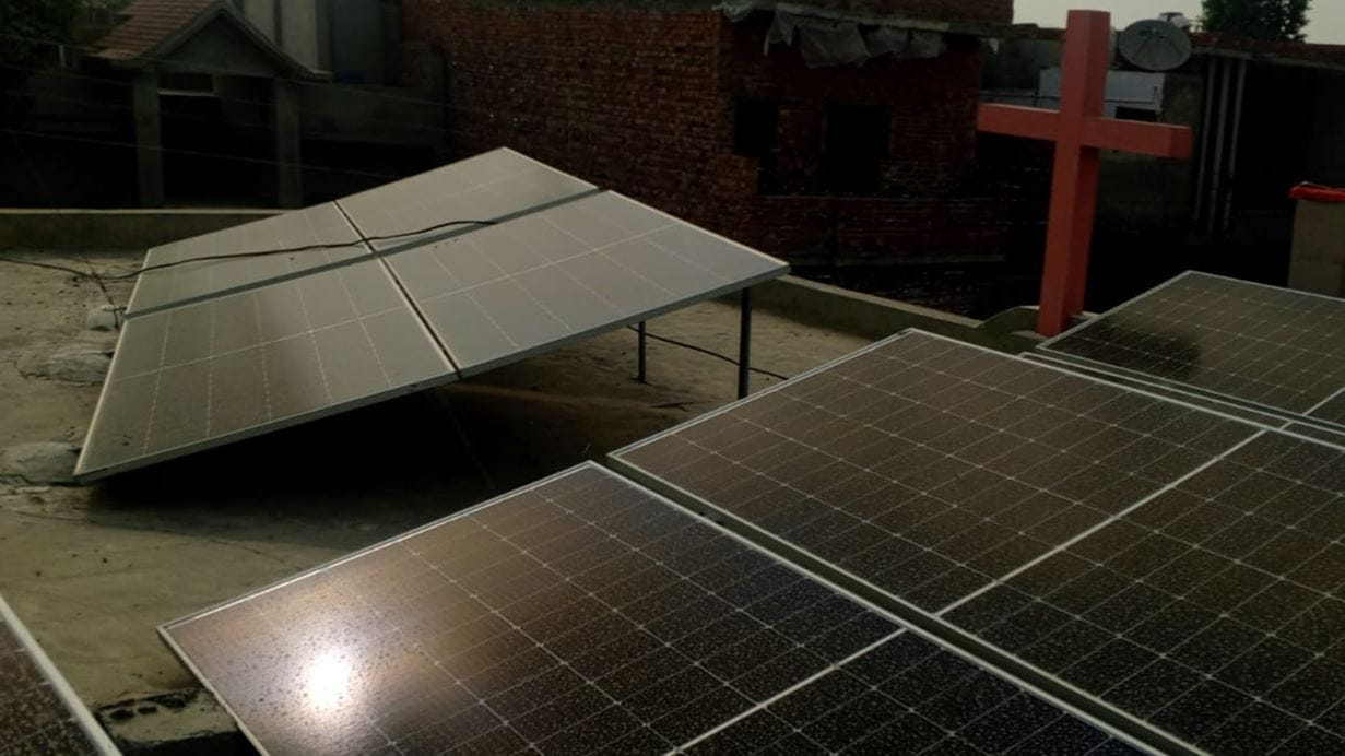 A cross and solar panels on the roof of a building.