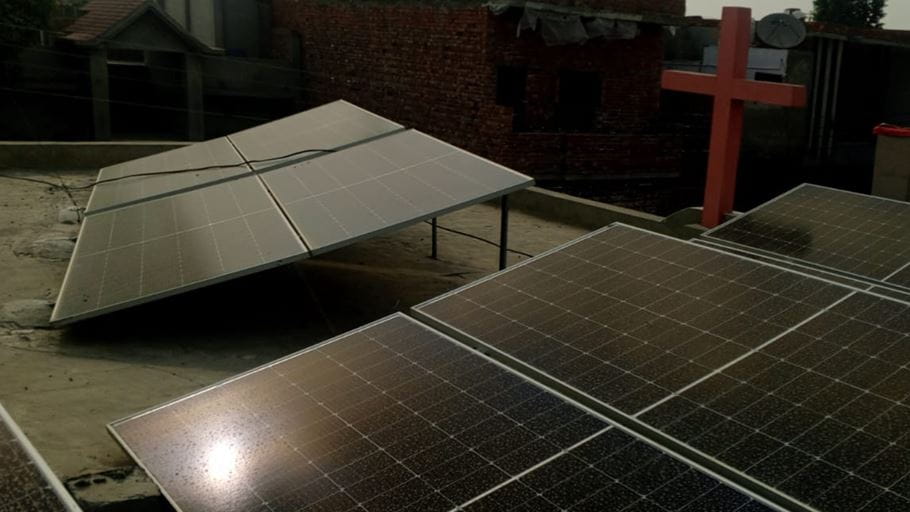 A cross and solar panels on the roof of a building.