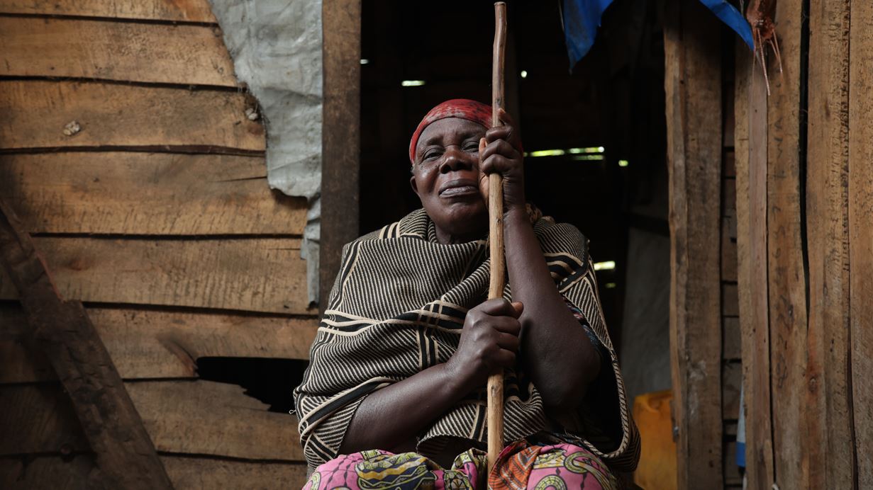A woman sits in front of a wooden shelter