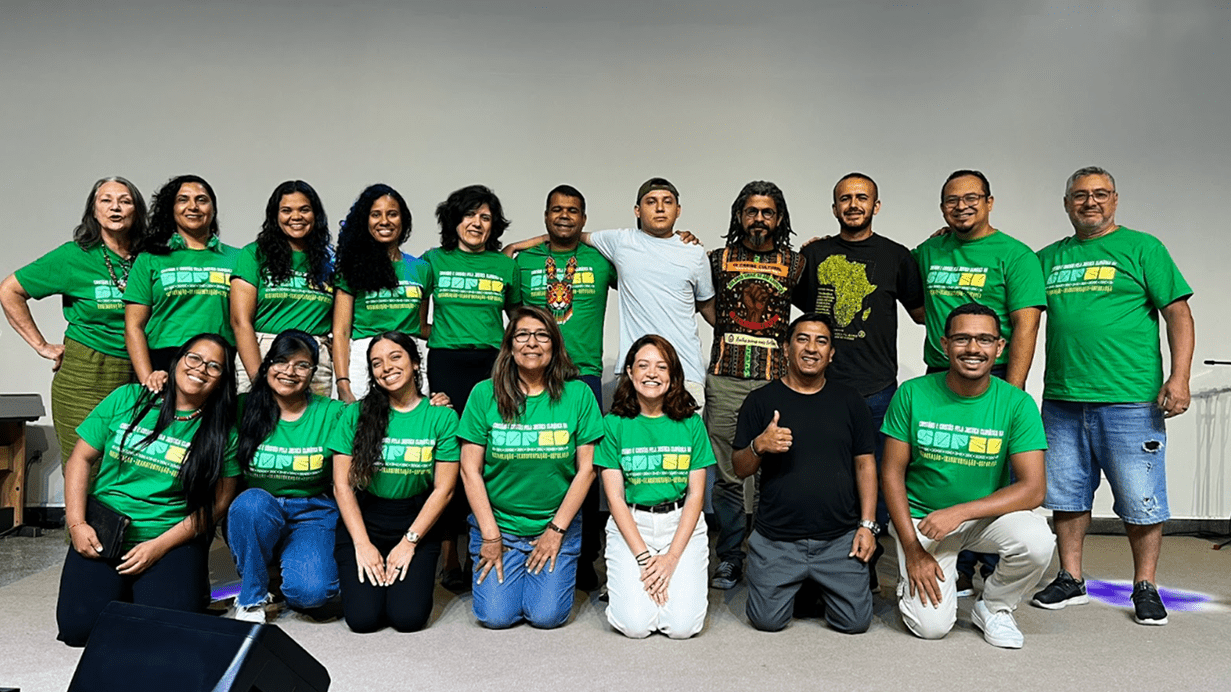 A group of volunteers pose together indoors for a photo, with many wearing matching green shirts and smiling.