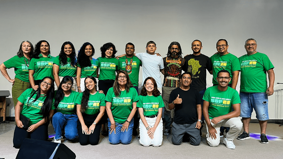 A group of volunteers pose together indoors for a photo, with many wearing matching green shirts and smiling.