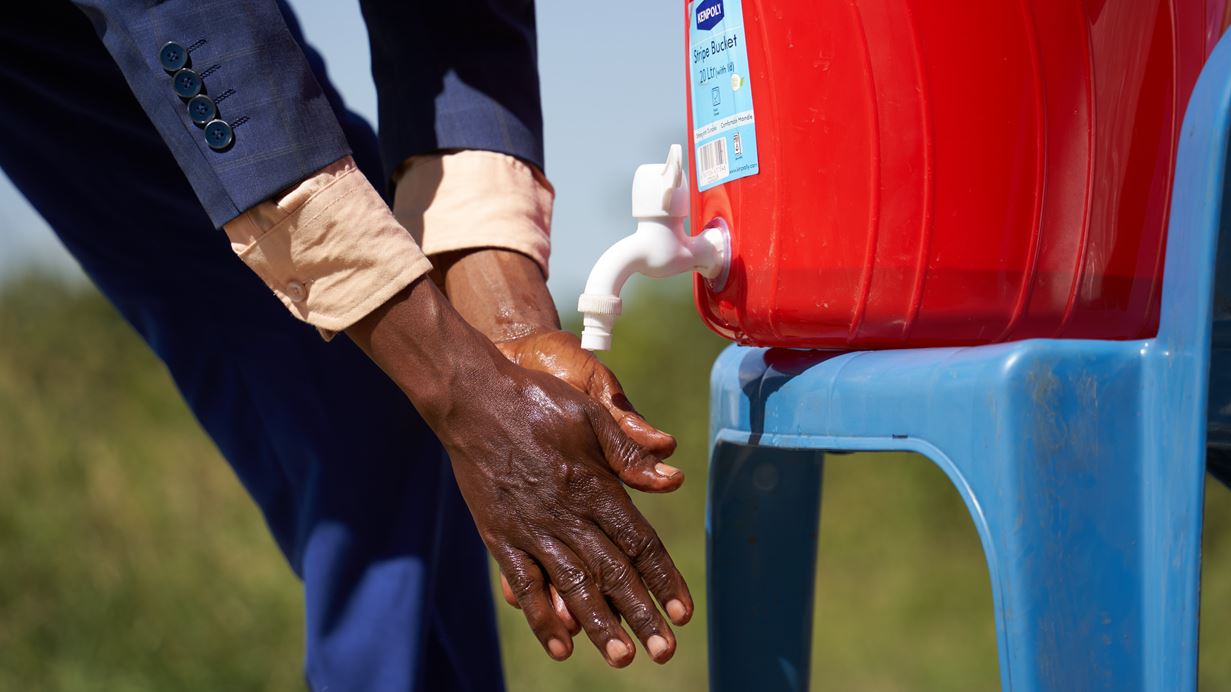 Hands being washed under a temporary tap