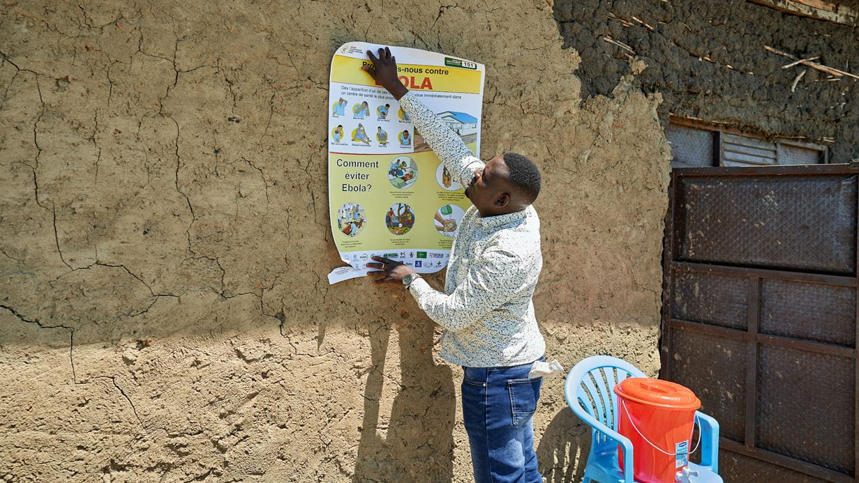 Man sets up a poster and a temporary tap outside a church building