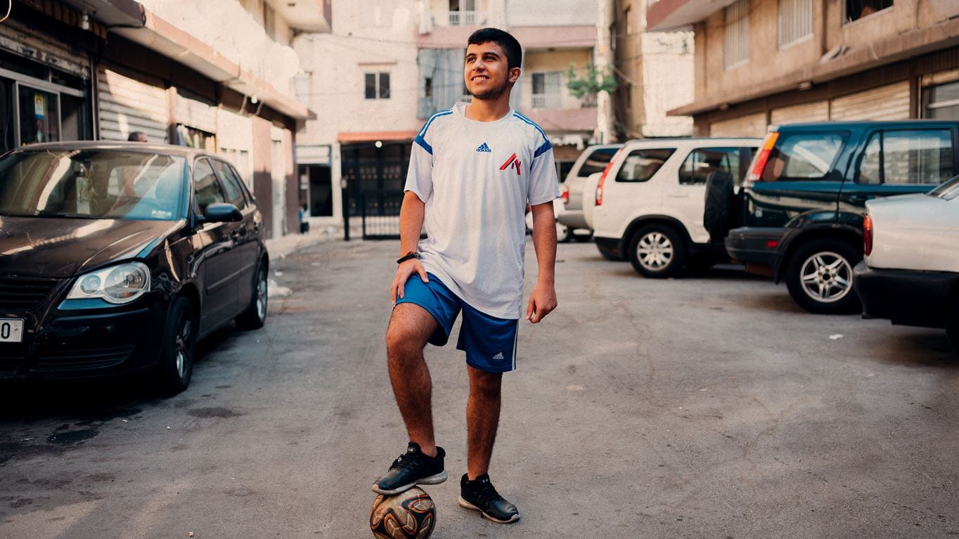 Saif stands with a football in a street in Beirut, Lebanon. Credit: Ruth Towell/Tearfund