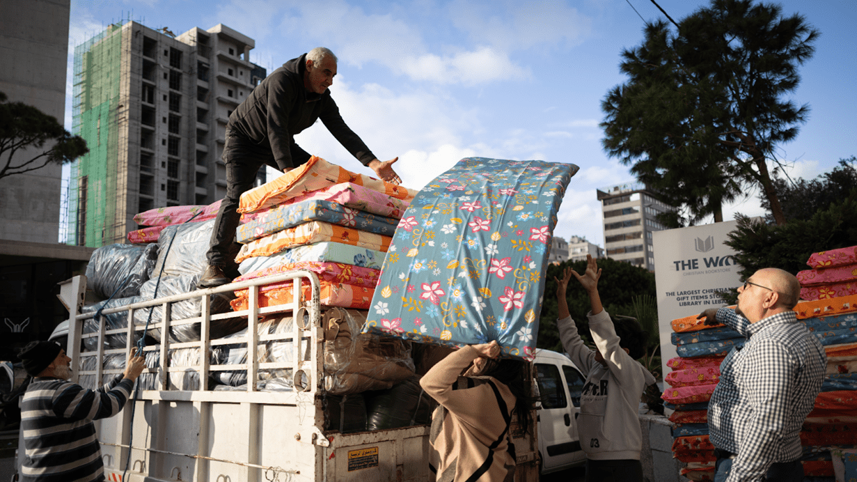 People unloading colorful mattresses from a truck parked on a city street.