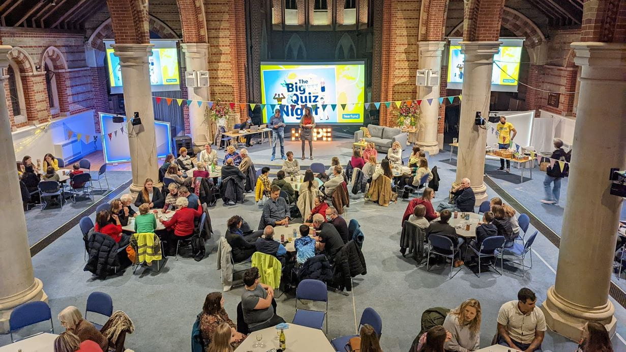 Groups of people take part in a quiz in a church hall