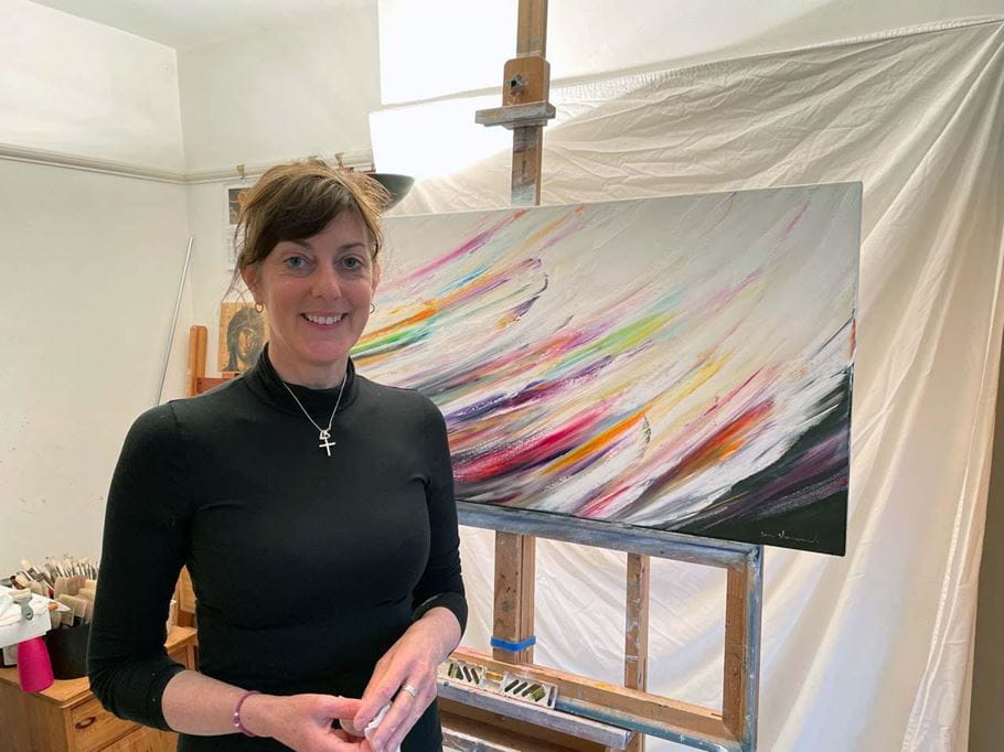 Sara Sherwood in her studio with the painting she created for Tearfund’s brief ‘Darkness into Light’