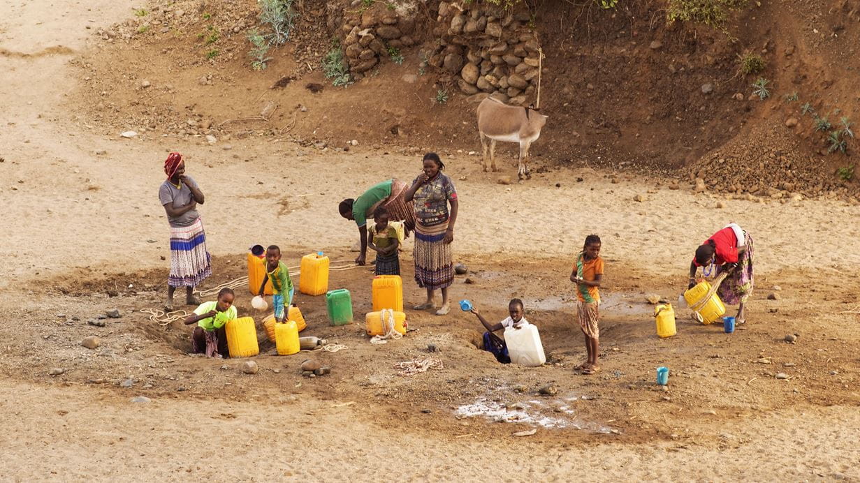 A group of adults and children with a variety of water containers